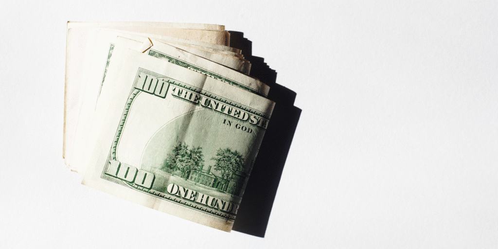 A stack of folded $100 bills fanned out on a white background