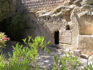 Rock-hewn tomb entrance surrounded by garden greenery and flowers at the Garden Tomb in Jerusalem