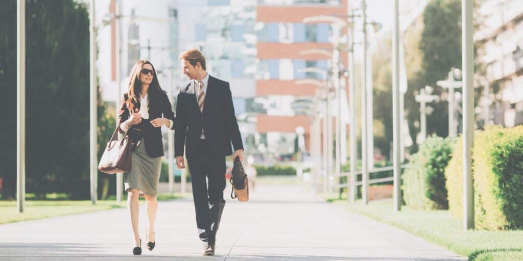 A man and woman walking and talking together outdoors.